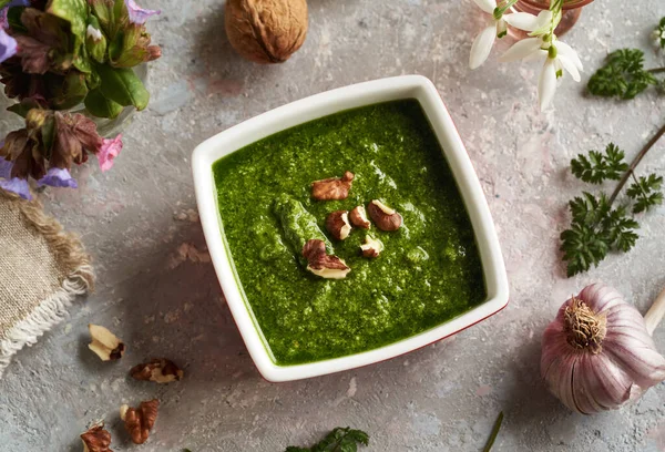 Pesto made of wild cow parsley leaves in early spring in a square bowl with walnuts and garlic