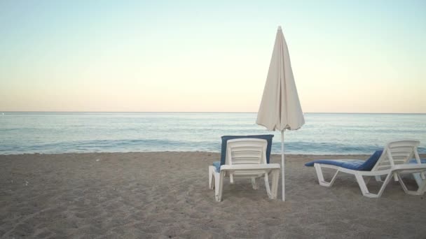 午前中にトルコの空のビーチで傘と座席 背景に形成された波と — ストック動画