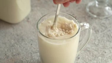 Masadaki bir bardak suyun içindeki beyaz protein tozunu karıştırıyorum.