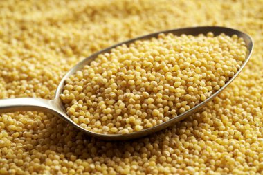 Peeled millet on a spoon, closeup clipart