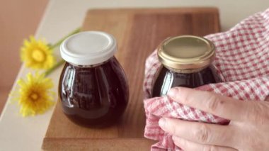 Sözüm ona karahindiba balı hazırlama. Yeni pişirilmiş sıcak bitkisel şurupla kaplanmış cam kavanozları ters çeviriyor.