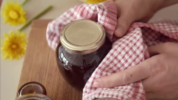 タンポポの蜂蜜を準備する 調理されたホットハーブシロップでキャップガラス瓶を裏返し — ストック動画