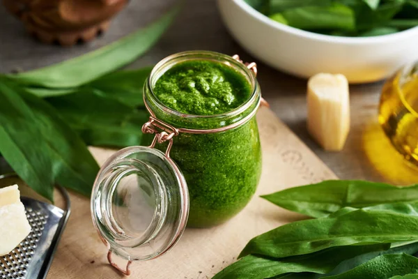 Taze sarımsak yaprakları, parmesan peyniri ve yağdan yapılmış bir kavanoz yeşil pesto.