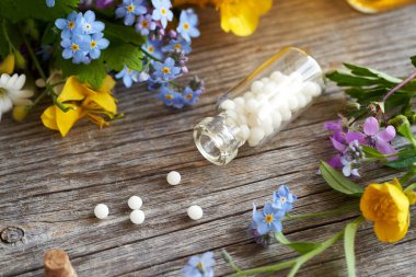 Bir şişe homeopatik hap ya da bahar aylarında renkli çiçekler ve bitkilerle dolu küreler.