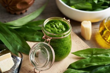 Parmesan peynirli taze sarımsak yapraklarından yapılmış bir kavanoz yeşil pesto sosu.