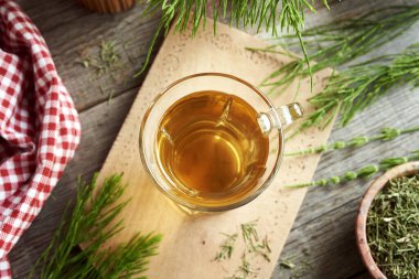 Taze ve kurumuş at kuyruğu bitkisi ile bir fincan bitki çayı.