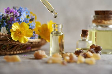 Bir damla aromaterapi, cam bir şişeye dökülen gerekli yağ, tütsü reçinesi ve bahar çiçekleri ile