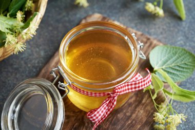 Haziranda toplanan ıhlamur çiçekleri ve yapraklarla dolu bir kavanoz bal.