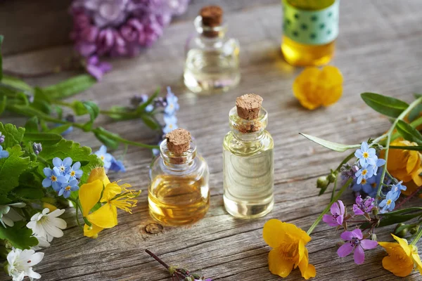 Masanın Üzerinde Renkli Bahar Çiçekleri Olan Aromaterapi Şişeleri — Stok fotoğraf