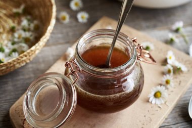 Cam bir kavanozda taze çiçeklerle yaygın papatya şurubu.