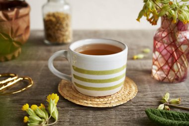 Taze inek ayağı ya da primula çiçekli bir fincan bitki çayı.