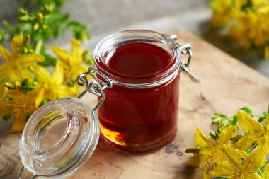 Baharın sonlarında toplanan taze çiçeklerle birlikte Red St. John 's marihuana yağı kavanozu.