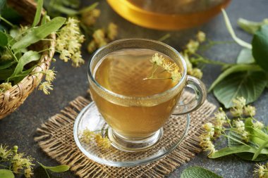 Taze ıhlamur veya Tilia kordata çiçekleri bir fincan bitkisel çayın içinde masada.