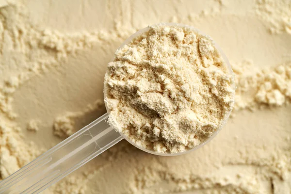 米黄色的乳清蛋白质粉末在一个塑料测量杯 顶部视图 健康营养补充剂 — 图库照片
