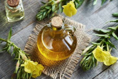 Taze Oenothera biennis çiçekleri ile ahşap bir masanın üzerinde cam bir şişedeki çuha çiçeği yağı