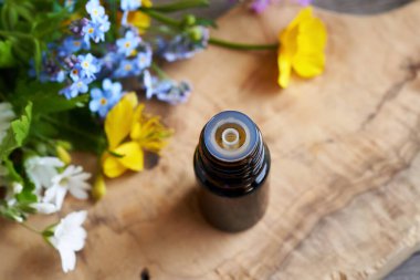 Renkli çiçekleri olan koyu renkli bir aromaterapi şişesi.