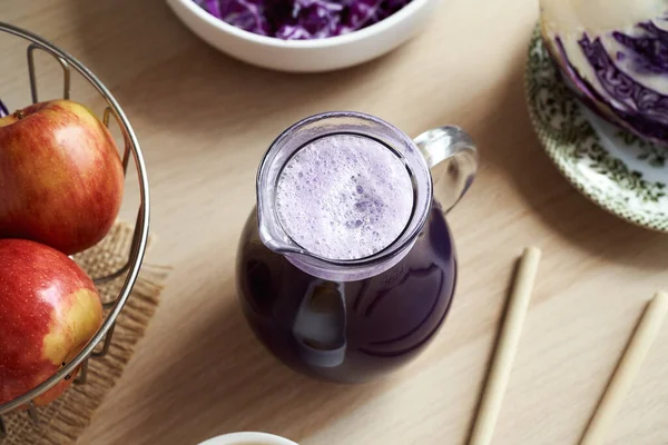 紫色卷心菜汁倒入一个装有苹果和竹签的玻璃瓶中 — 图库照片