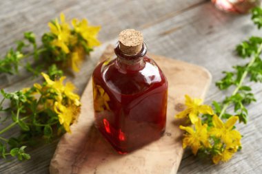 Bir şişe ev yapımı kırmızı yağ taze St. John otundan ya da masadaki Hypericum çiçeklerinden yapılır.