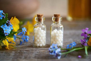 Renkli çiçeklerle dolu cam şişelerde homeopatik küreler