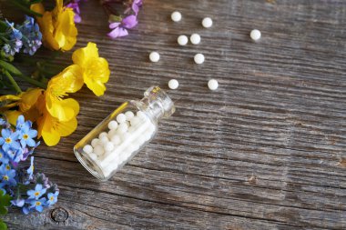 Bir şişe homeopatik hap. Baharda rengarenk çiçekler ve fotokopi alanı.