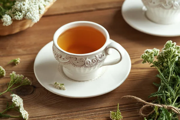 stock image A cup of herbal tea with fresh yarrow flowers on a wooden table