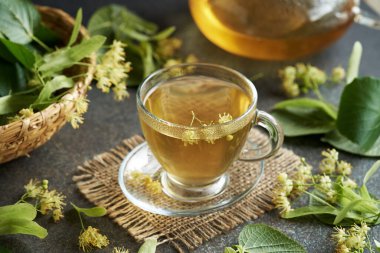 Cam bir fincanda masanın üzerinde ıhlamur çiçeği çayı.