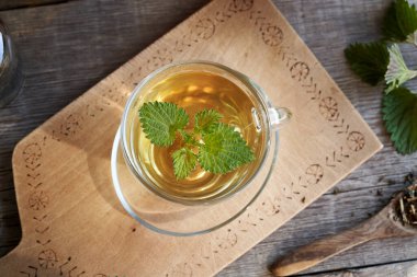 Tahta bir masanın üstünde bir fincan ısırgan otu çayı.