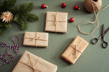 Yeşil zemin üzerinde köknar ağacı dalları olan ekolojik geri dönüşümlü kağıda sarılmış Noel hediyesi