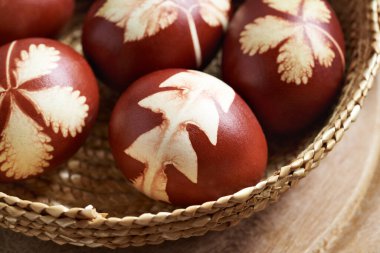 Kahverengi Paskalya yumurtaları soğan kabuklarıyla boyanmış, çeşitli yapraklarla boyanmış.