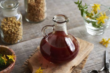 St. John 's otu ya da masadaki cam sürahide Hypericum yağı.