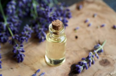 Ahşap bir masa üzerinde taze lavanta çiçekleri olan bir şişe aromaterapi.