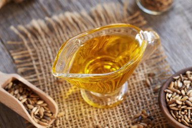 Arka planda Carduus marianus tohumları olan bir sürahi süt devedikeni yağı.