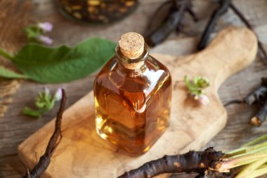 Taze papatya ya da örgü kökü olan bir şişe bitkisel tentür.