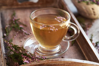 Bir fincan bitki çayı tepside taze çiçek açmış fundalarla ya da Calluna vulgaris bitkisiyle