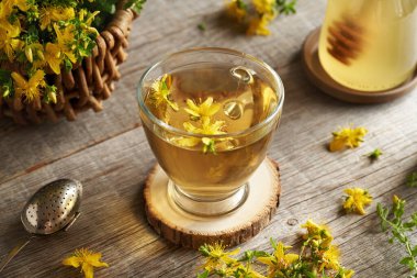 Masasında taze Hypericum çiçekleri olan bir fincan St. John 's Wort çayı.