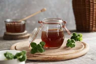 A jar of Plectranthus amboinicus syrup for common cold on a table clipart