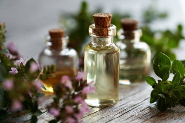Masada taze çiçek açan kekik bitkisi olan gerekli yağ şişeleri.
