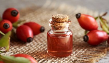 Masanın üzerinde şeffaf bir şişe gül tohumu yağı.