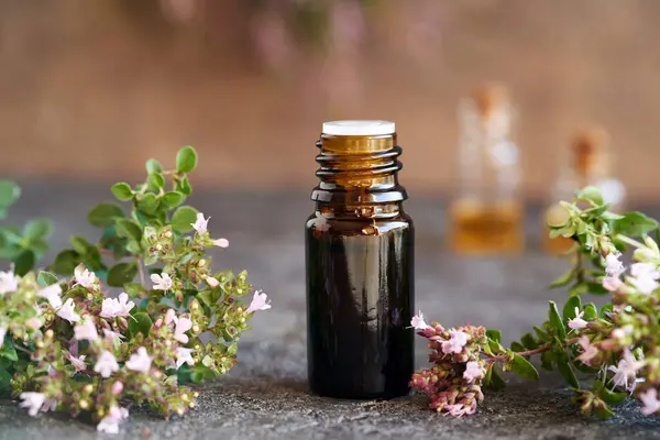 Oregano essential oil in a brown dropper bottle, with fresh blooming plant