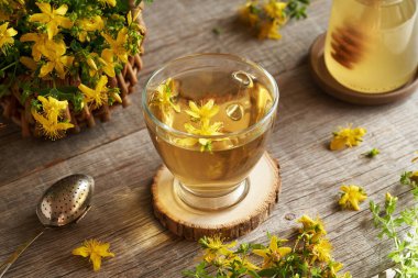 Masada taze Hypericum çiçekleri olan bir fincan St.John otu çayı.