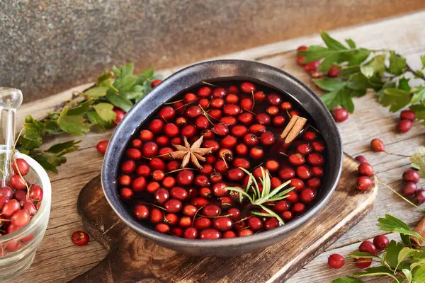 Macerating fresh hawthorn berries, cinnamon and spices in red wine to prepare medicinal drink