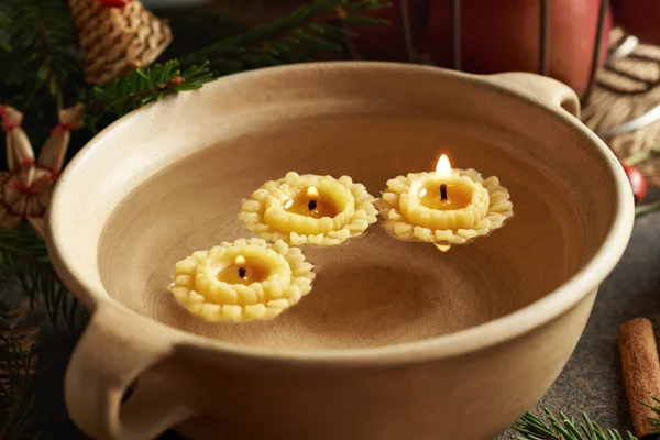 Candles made from bees wax floating in a bowl of water at Christmas