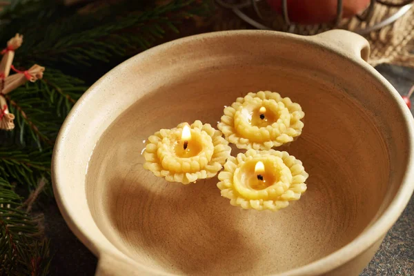 Christmas candles made of bees wax floating in a bowl of water