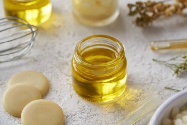 Bir kavanoz yağlı kakao yağı, balmumu topakları ve bitkilerle