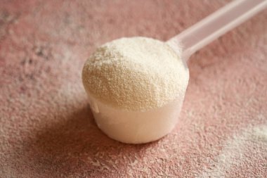 Plastik bir ölçü kabındaki kolajen tozu, yakın plan.