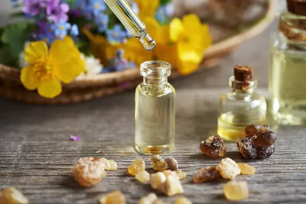 A bottle of aromatherapy essential oil with a dropper and spring flowers
