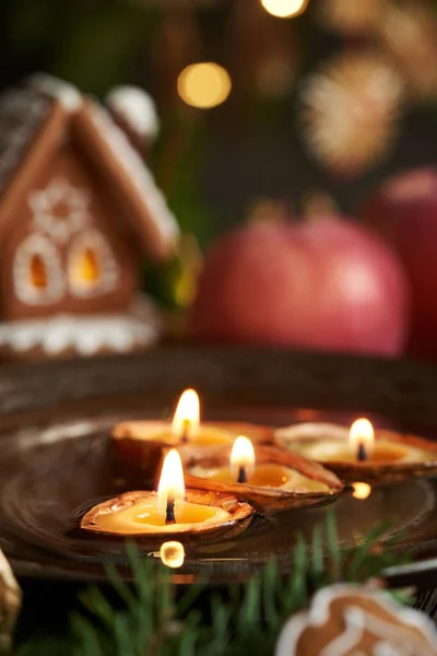 Christmas candles made of bees wax floating in water, with a gingerbread house in the background