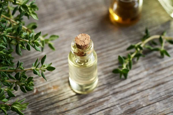 Aromatherapy essential oil with fresh thyme twigs on a table