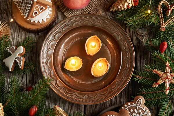 Christmas nut candles made of bees wax floating in a water, with gingerbread cookies around