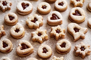 Ev yapımı Linzer Noel kurabiyeleri marmelatla dolu ve masaya şeker serpiştirilmiş.